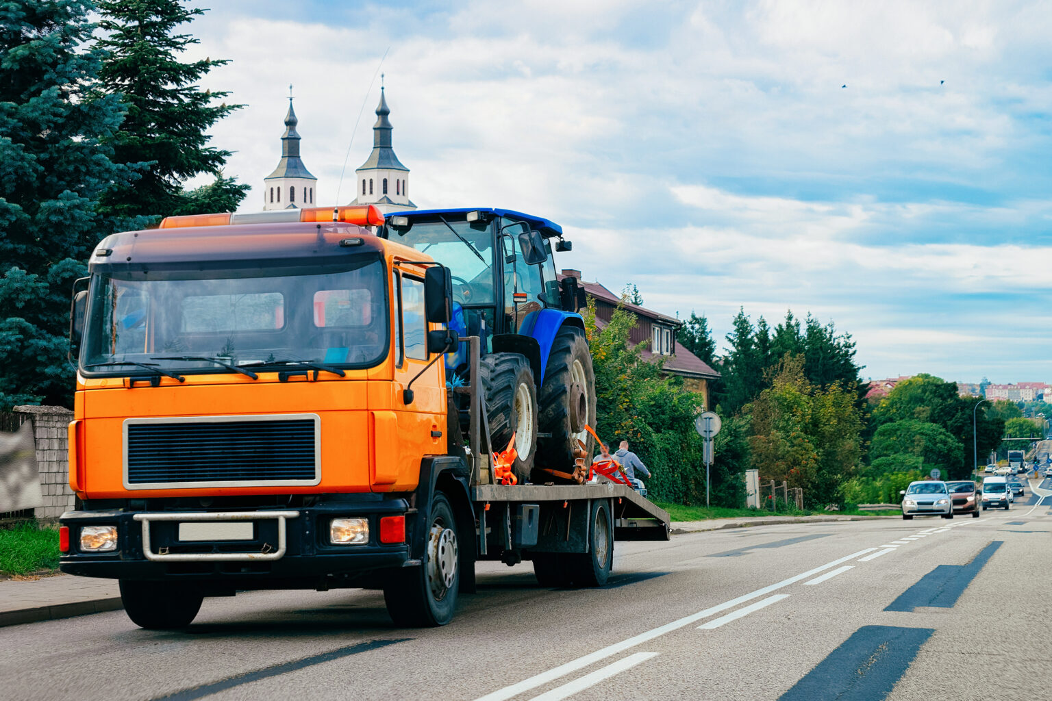 Truck trailer transporter with hauler carrying agricultural tractor on the road in Poland.